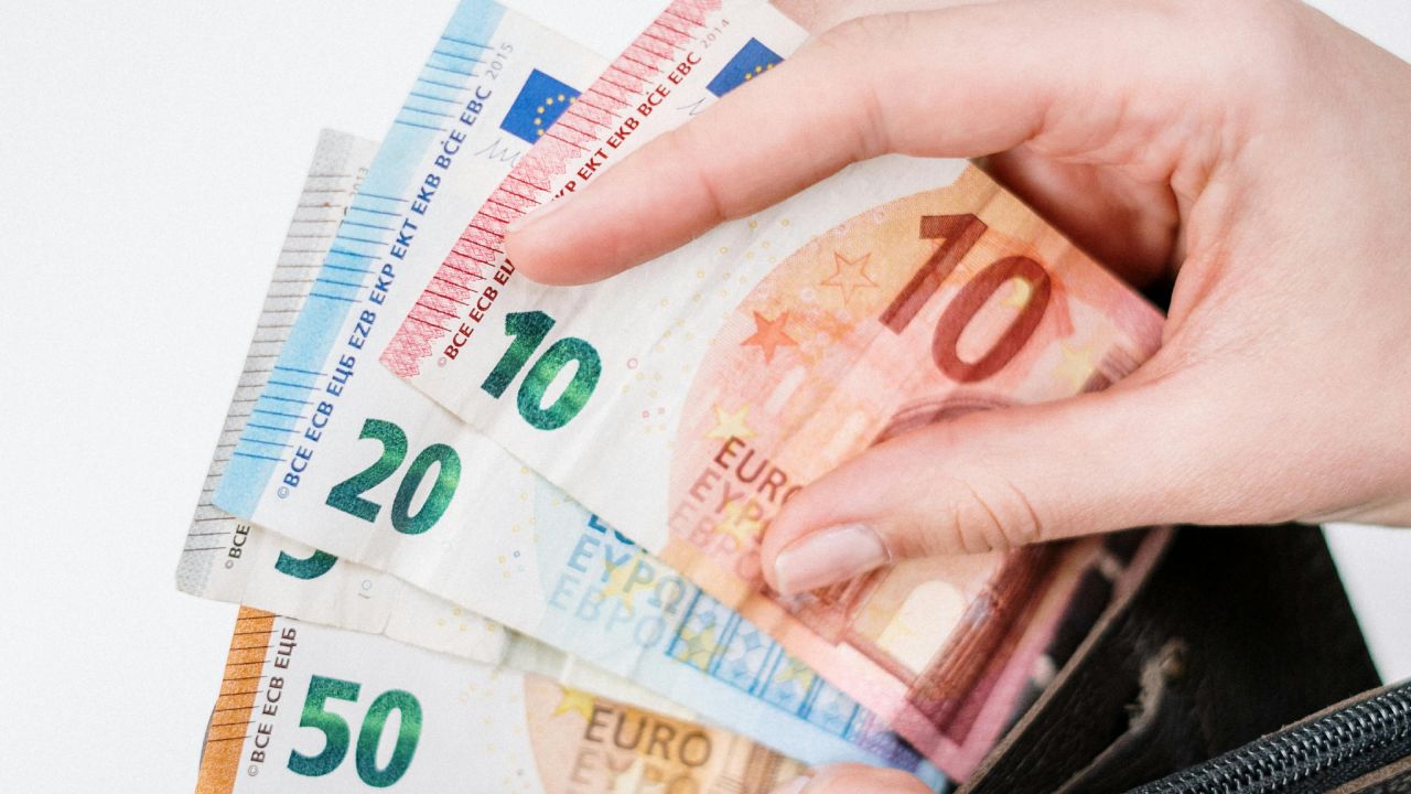 Persona che tira fuori delle banconote dal portafoglio